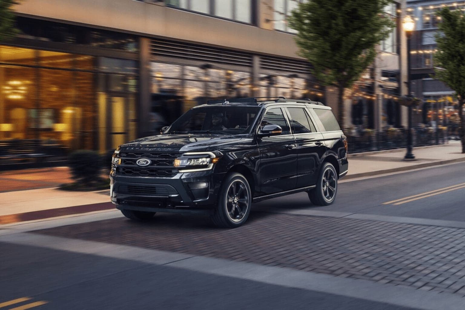 Black Ford Expedition in motion on urban street at dusk