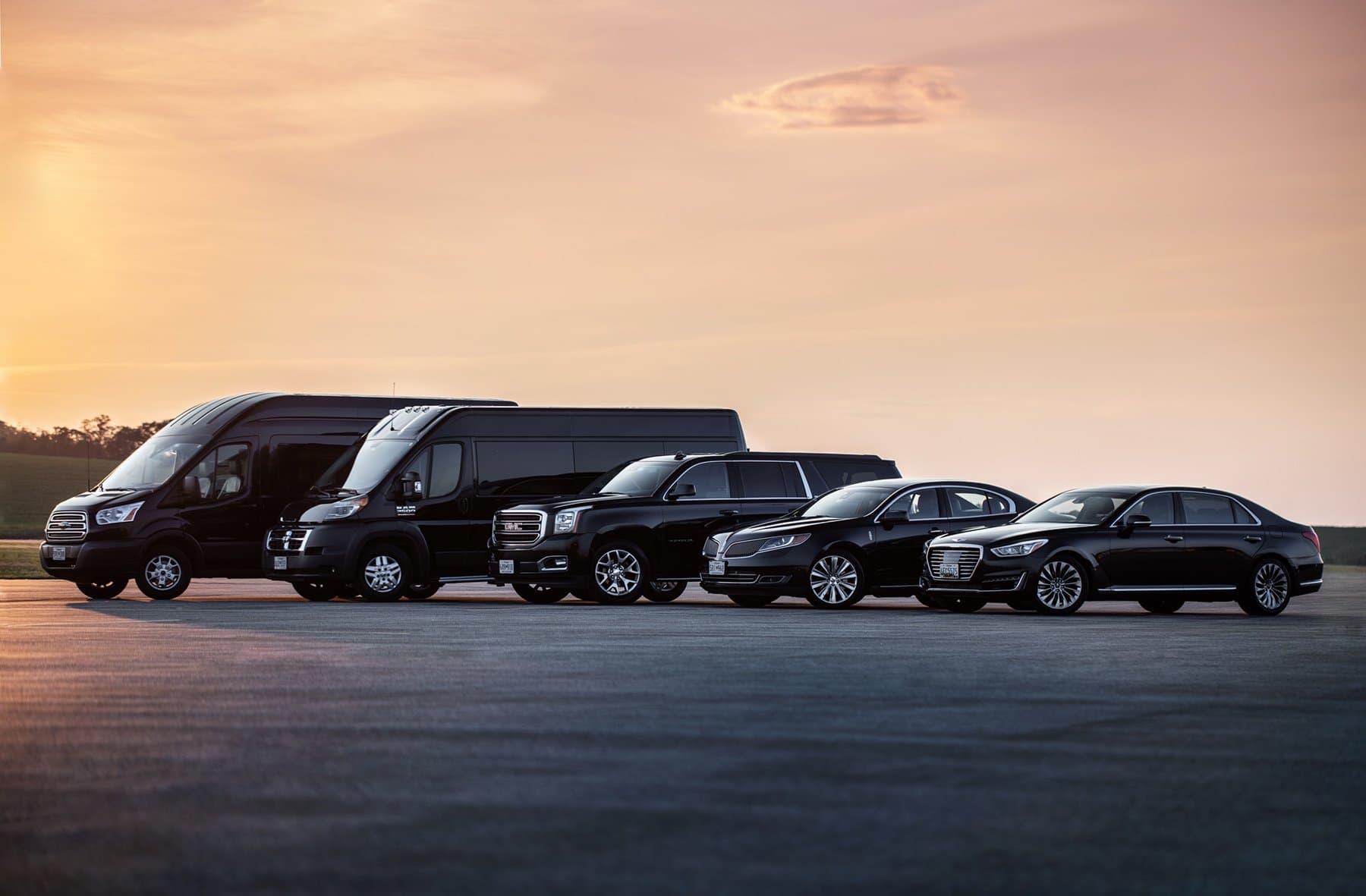 Professional lineup of black luxury vehicles on tarmac at golden hour
